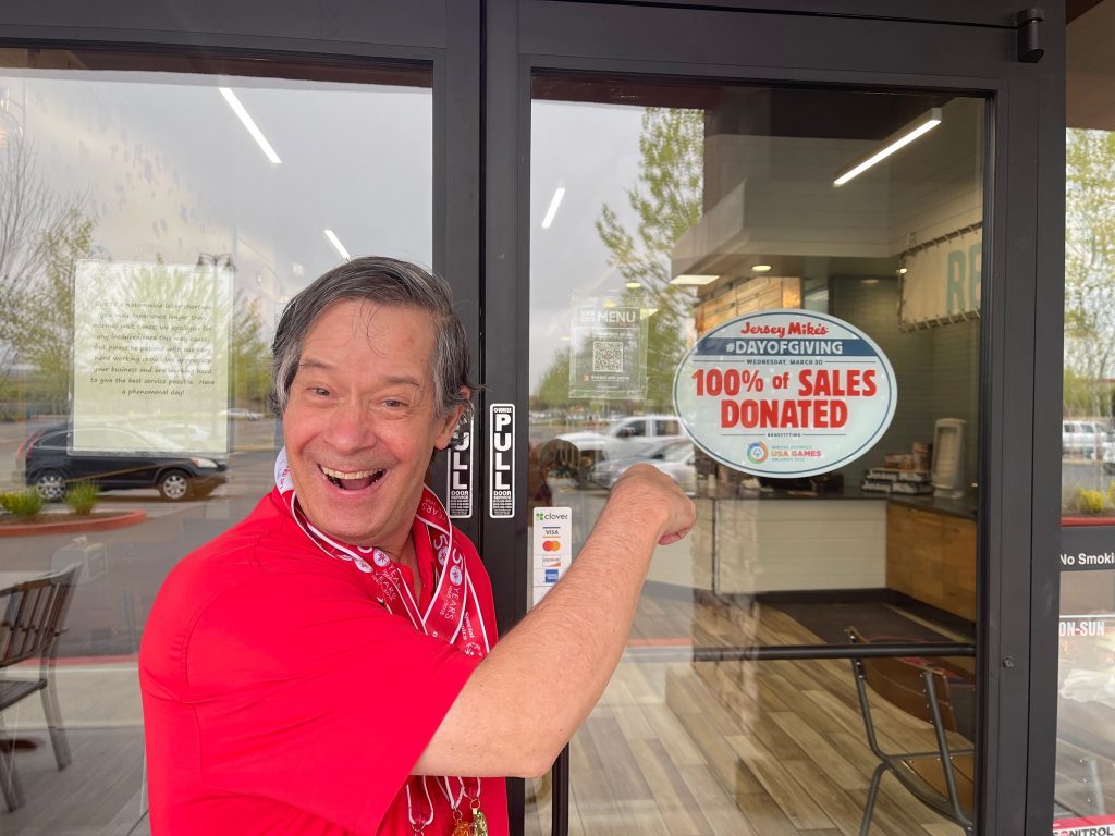 Jersey Mikes - Athlete pointing to "Day of Giving" door sticker