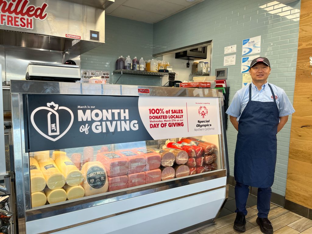 Jersey Mikes - Employee in front of "Month of Giving signage"