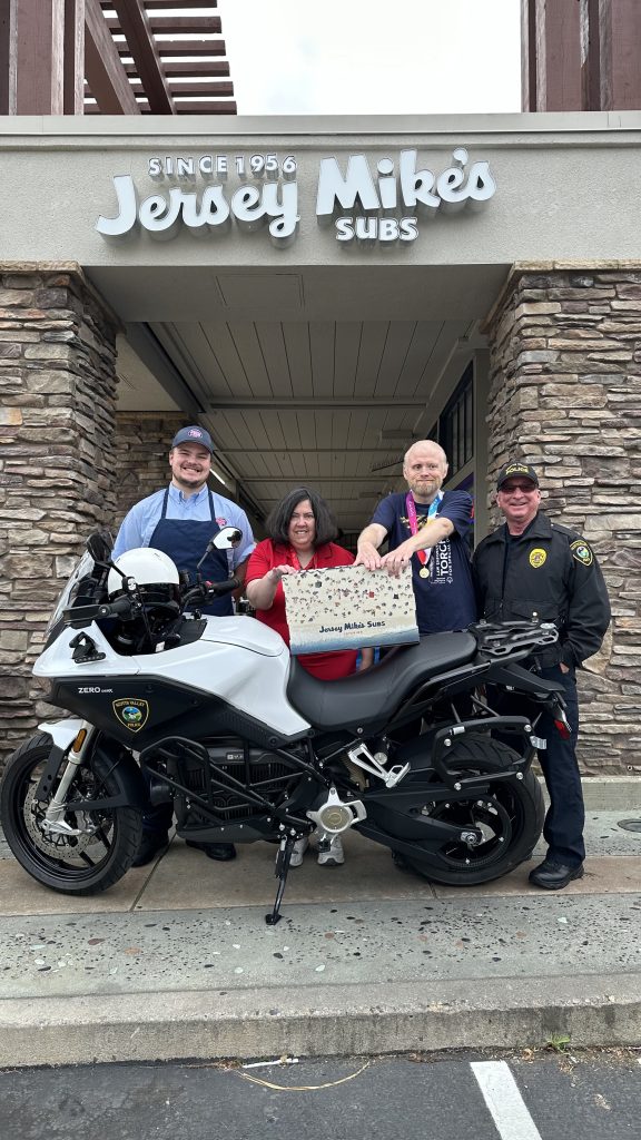 Jersey Mikes - Jersey Mike's employee, athletes, and police officer in front of storefront