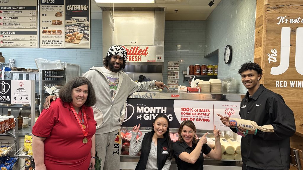 Jersey Mikes - People pointing to "Month of Giving" signage